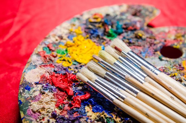 An artist's palette covered in acrylic paints and mica powder.