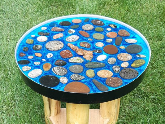 A blue epoxy resin table top made using Pigmently Epoxy Pigments and various minerals and stones as decorations..