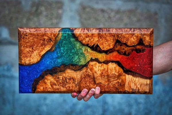 A wooden epoxy sample piece, showcasing several different powder pigments of blue, green, yellow, and red.