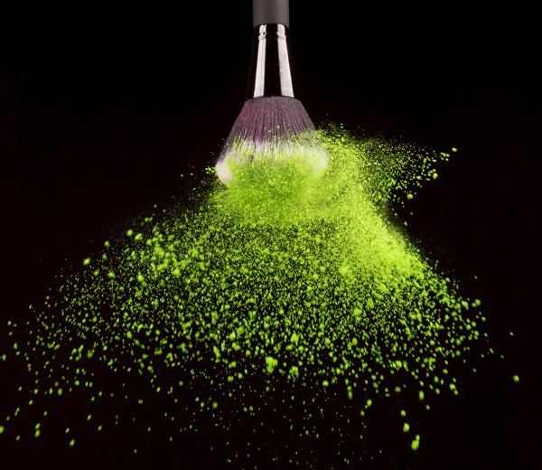 Green pigment powder falling off of a spinning brush.