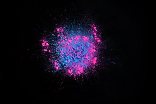 Two neon mica powders spread on a pitch black surface.