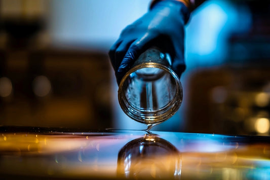Epoxy resin mixed with mica powder being poured from a clear plastic cup onto a surface.