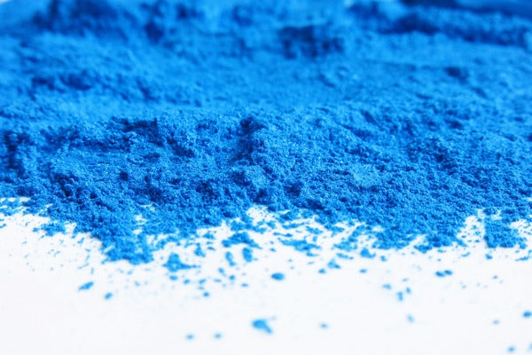 A small mound of blue mica powder on a white table surface.